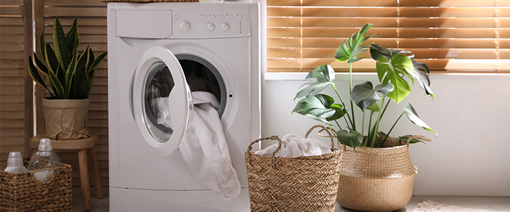 Weiße Waschmaschine die im Badezimmer steht, gefüllt mit Wäsche