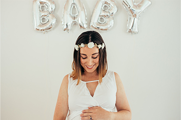 Schwangere Frau, im Hintergrund Buchstaben-Luftballons 