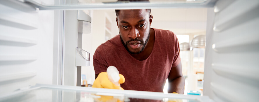Mann beim Kühlschrank innen reinigen