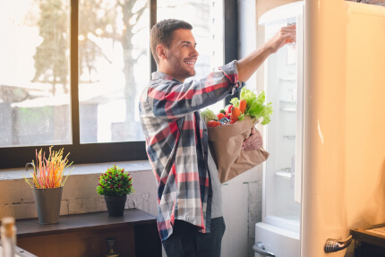 Mann beim Kühlschrank einräumen