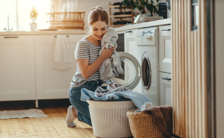 Frau freut sich über weiche Wäsche aus der Waschmaschine